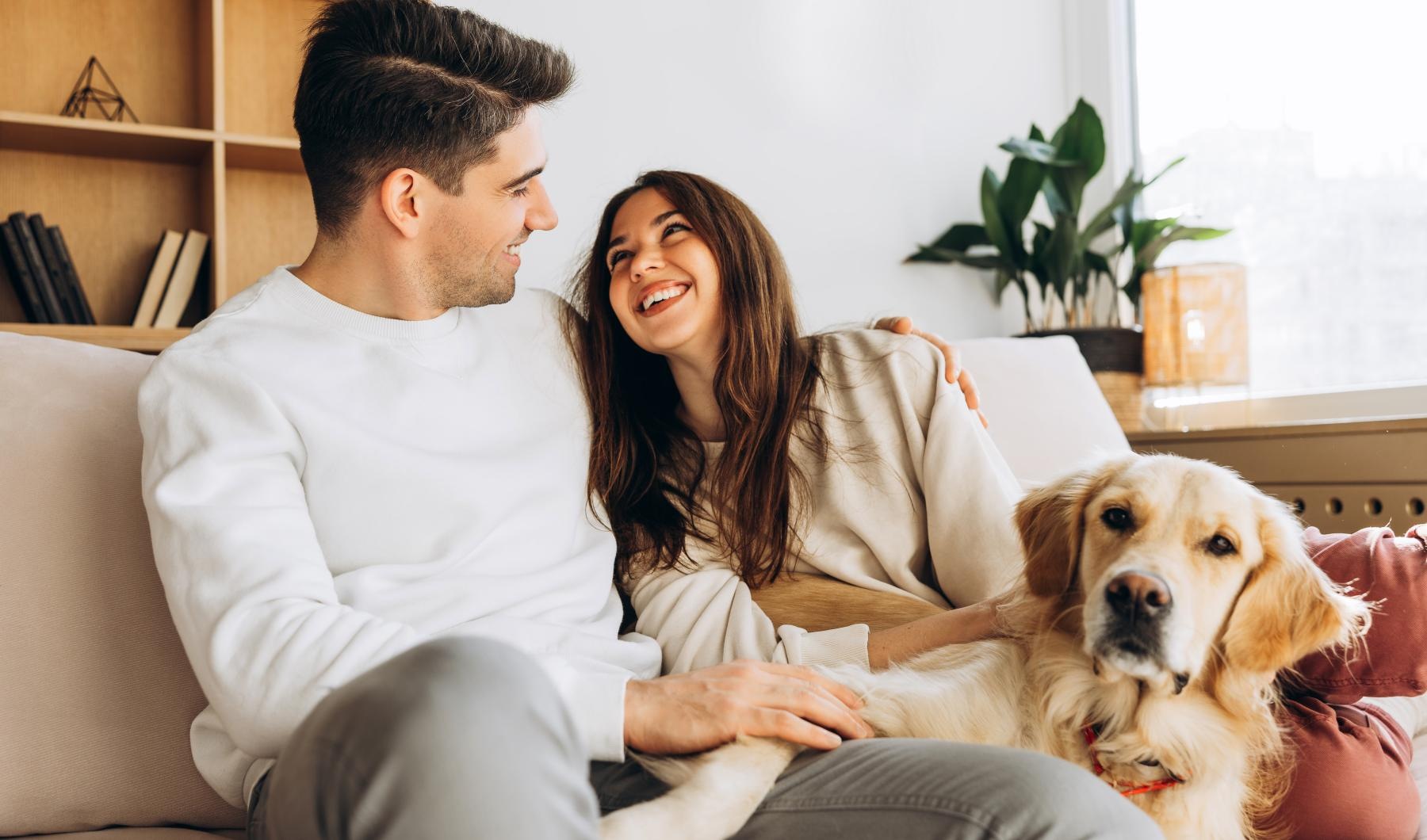 a man and woman sitting on a couch with a dog